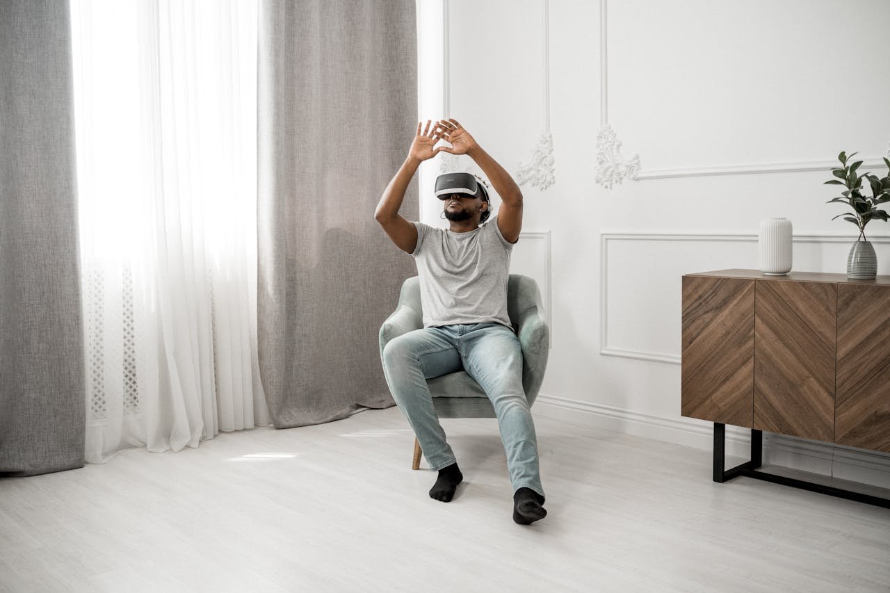 A man sitting in a chair wearing VR glasses, immersed in a virtual reality experience at home.